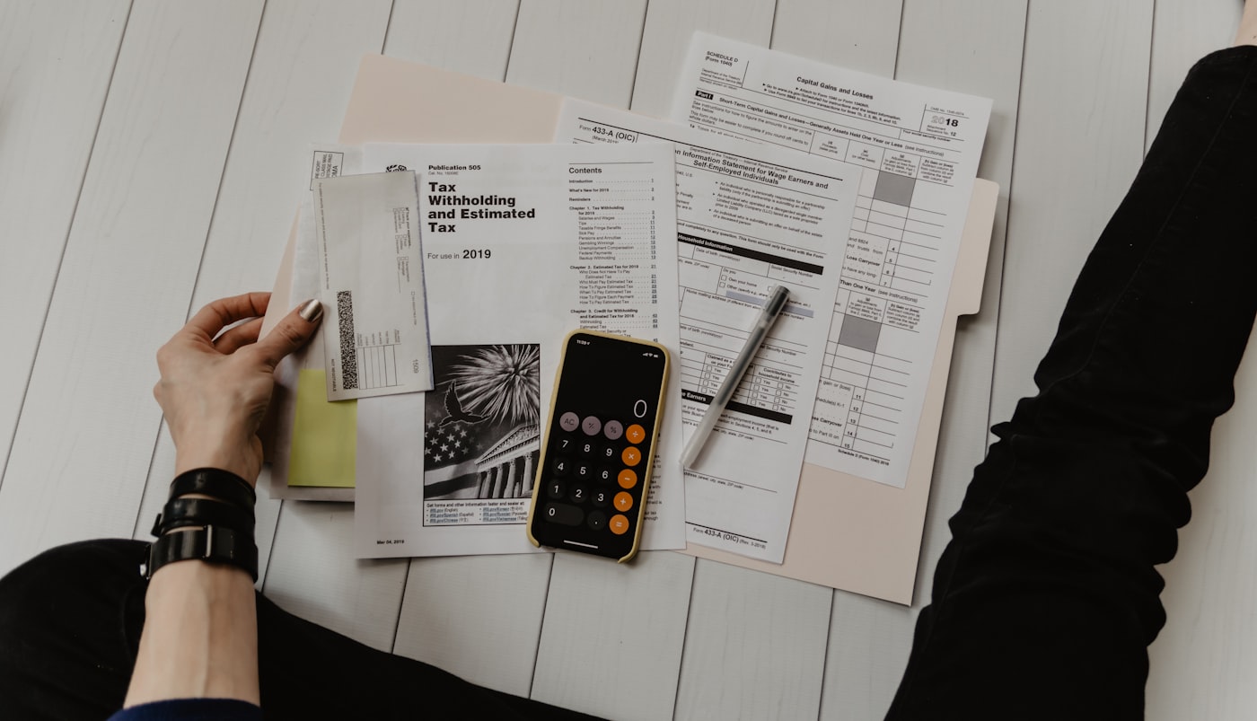 Tax forms, a calculator, and a pen laid out neatly on a desk