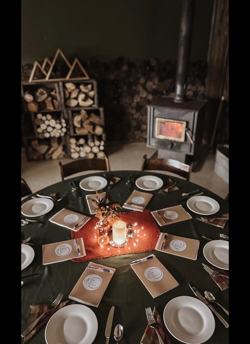 A candlelit table setting with place cards and a fall centerpiece