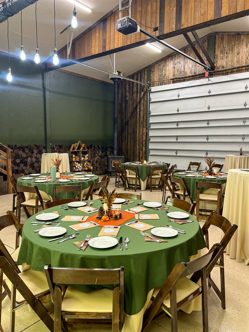 Round tables dressed in green linens with autumn place settings in the event space